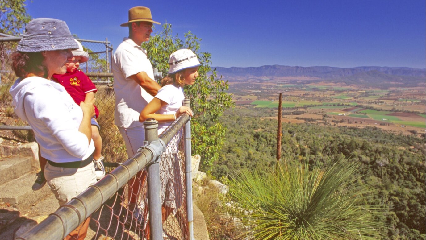 Young family at high lookout with views over bushland, farmland and mountains.