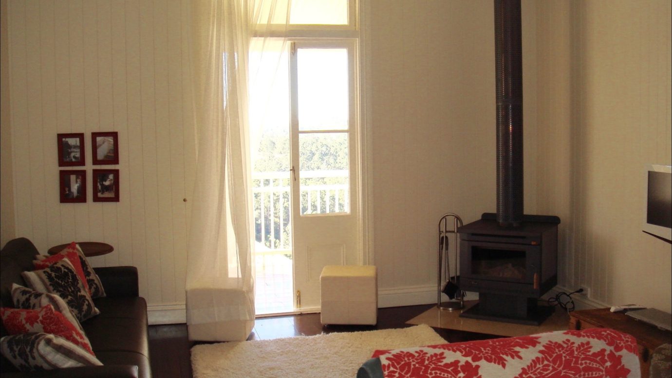 Lounge room with fireplace, french doors to side verandah, white rug on the floor