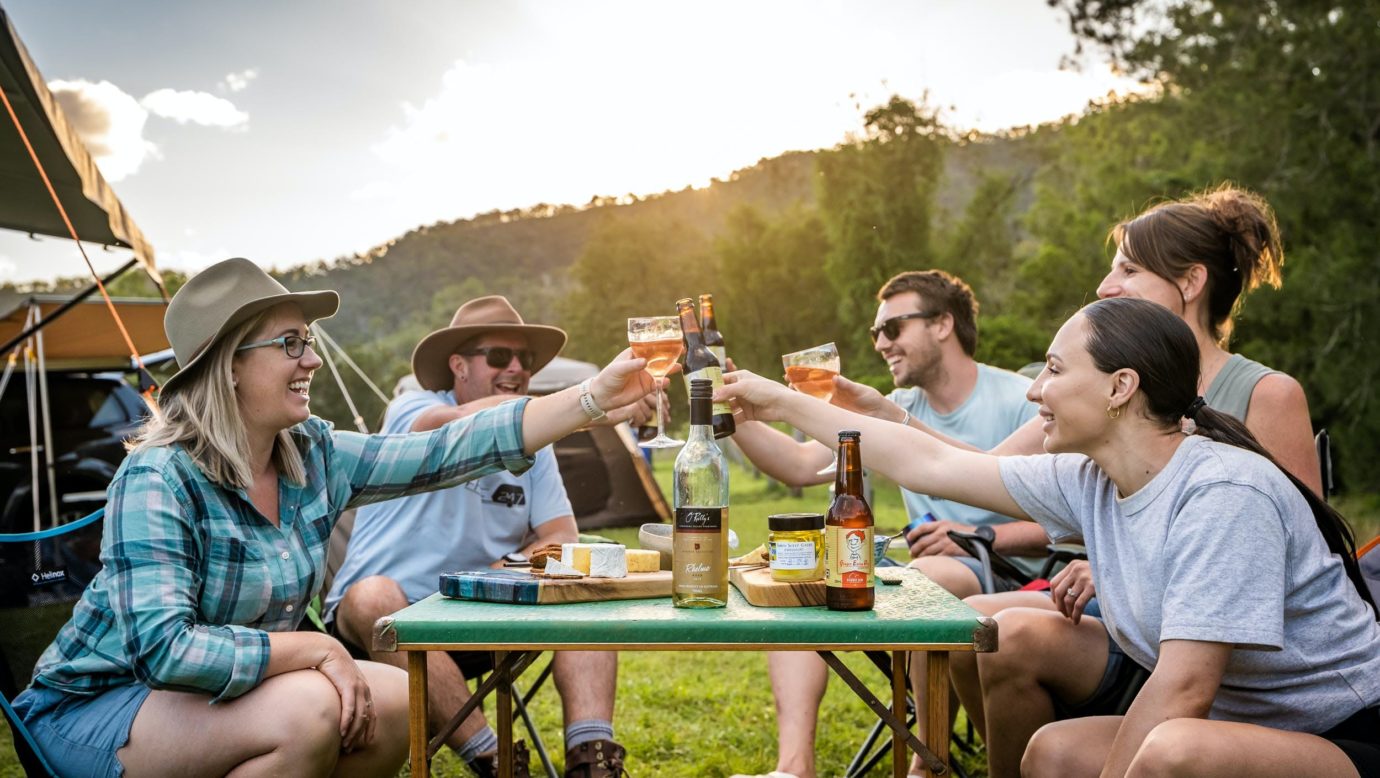 Friends sitting around a camping table with cheese, wine and beer at Kerry Valley Secret.