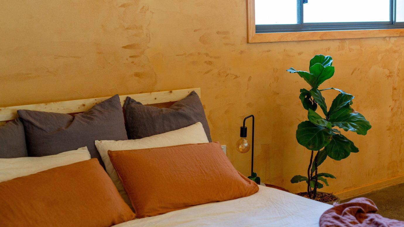 bedroom with natural linen, clay walls and plant at cabin