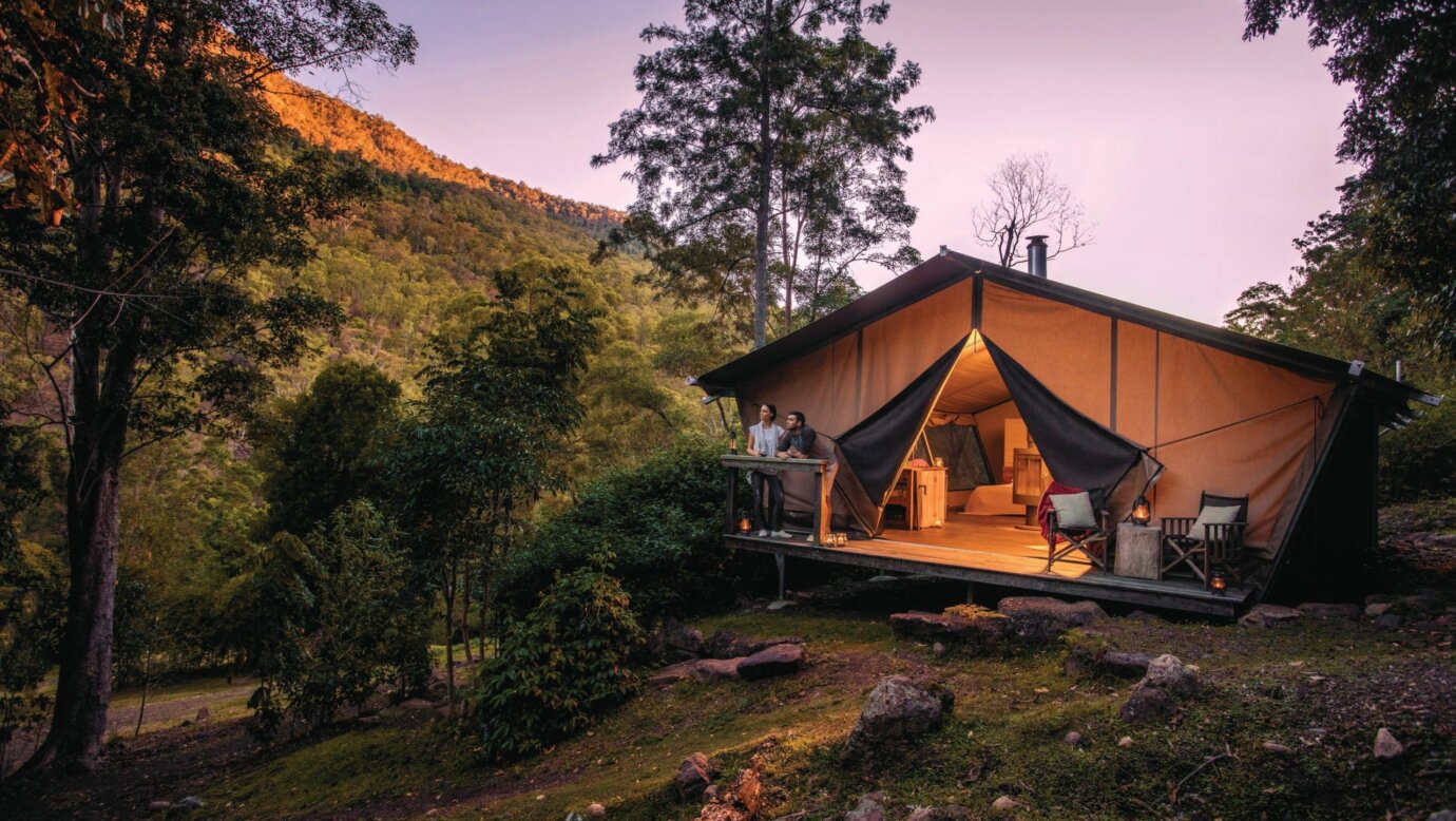 Romantic couple enjoy the change in light from the safari tent deck as night falls.