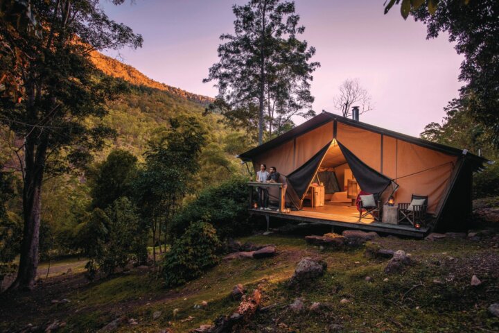 Romantic couple enjoy the change in light from the safari tent deck as night falls.