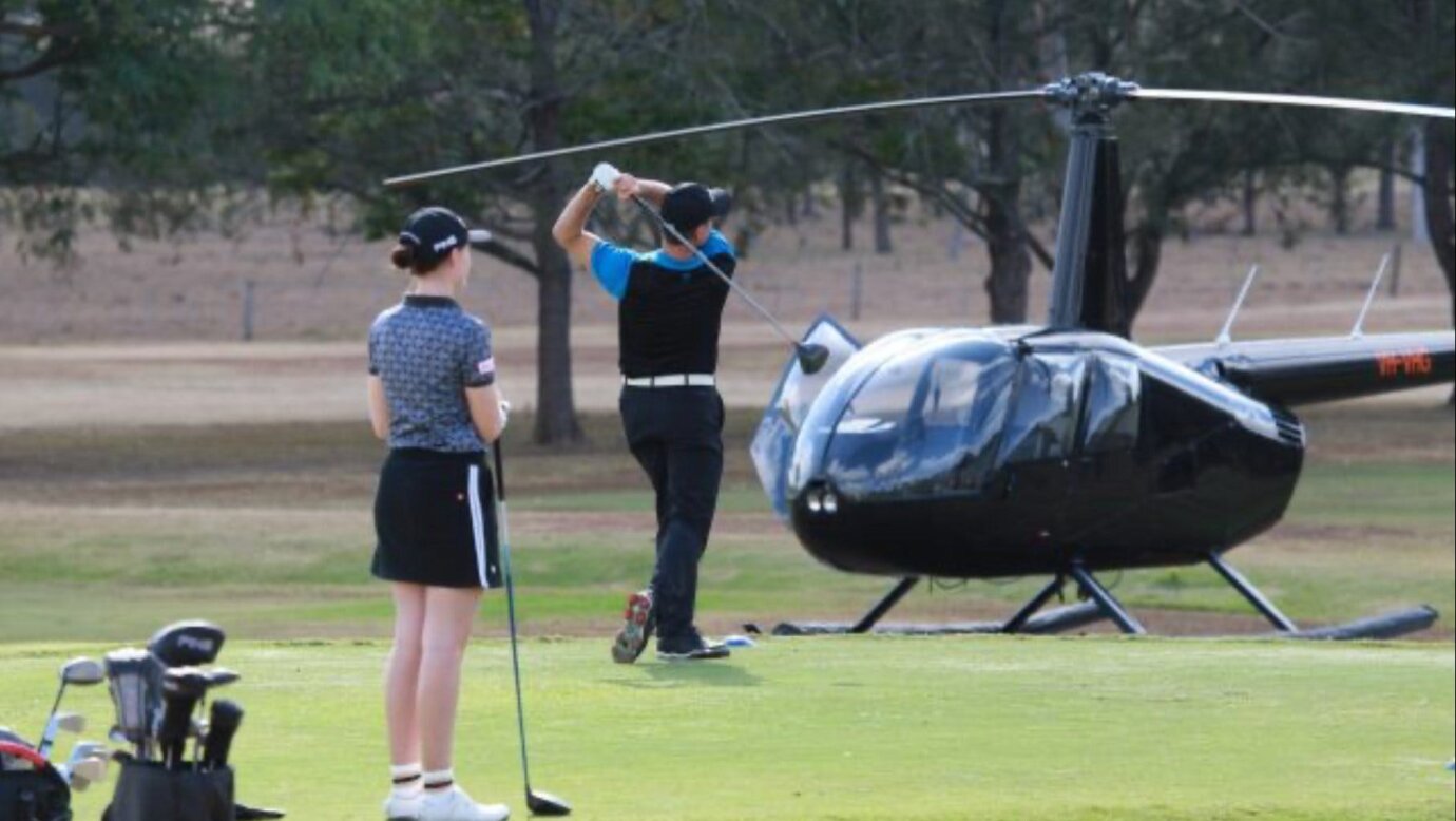 Couple playing golf with helicopter in background