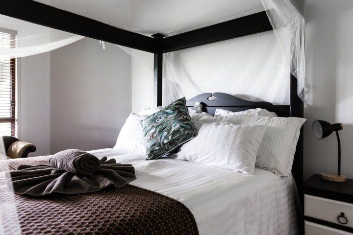 4 poster bed with white linen and maroon and teal bedding