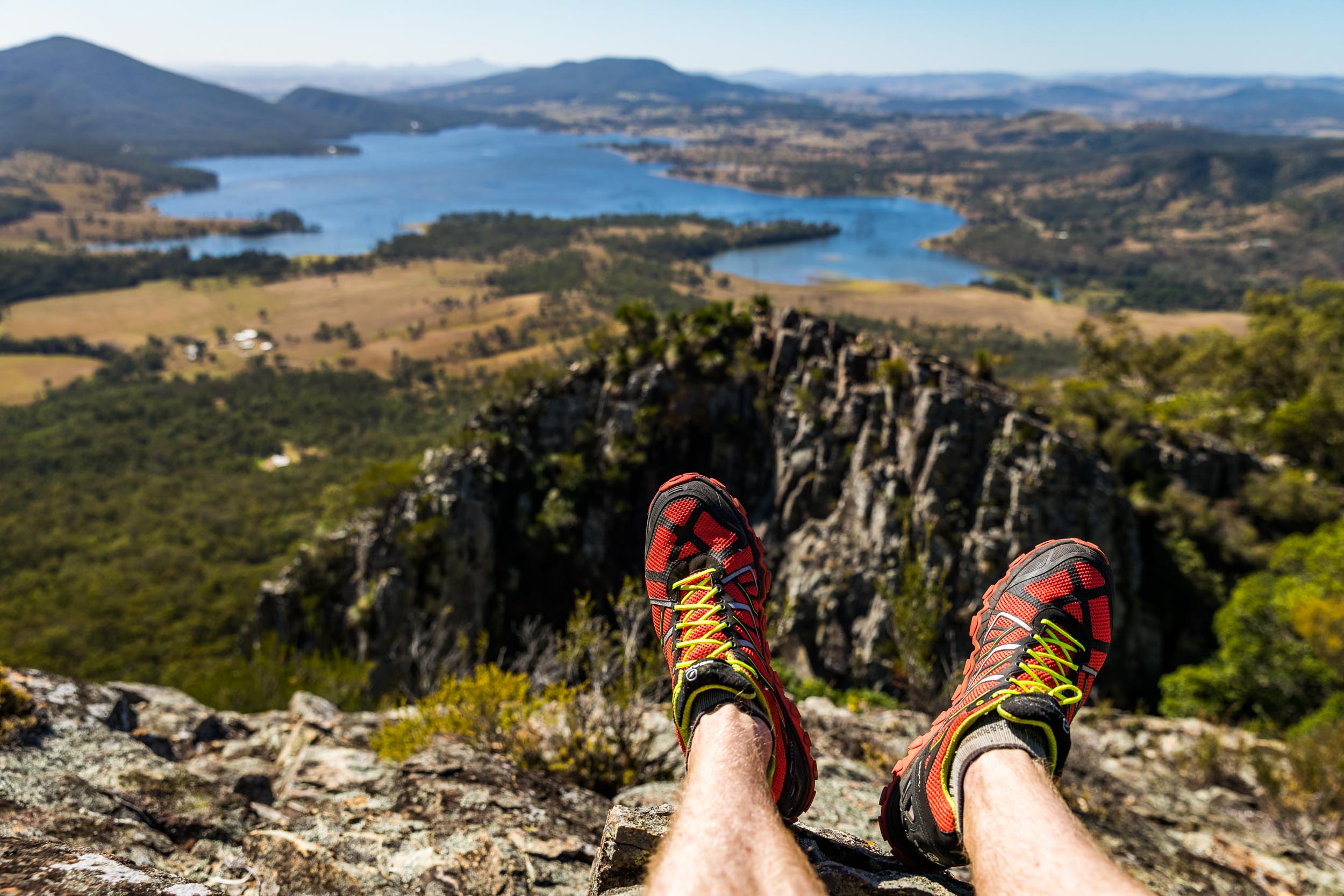 Hiker's feet wearing walking boots, looking over Lake Moogerah from Mount Greville