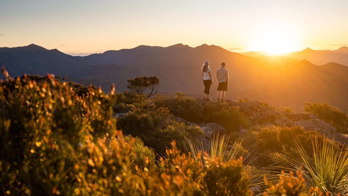 Epic adventures within the Scenic Rim, two hikers view the sunset on Mount Maroon in the Scenic Rim, Queensland, Australia