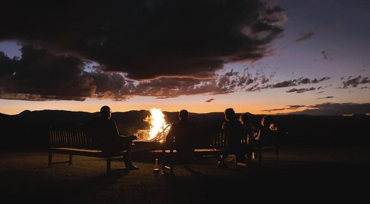 Winter escape group sitting around an outdoor fire pit at Mt French Lodge, Scenic Rim