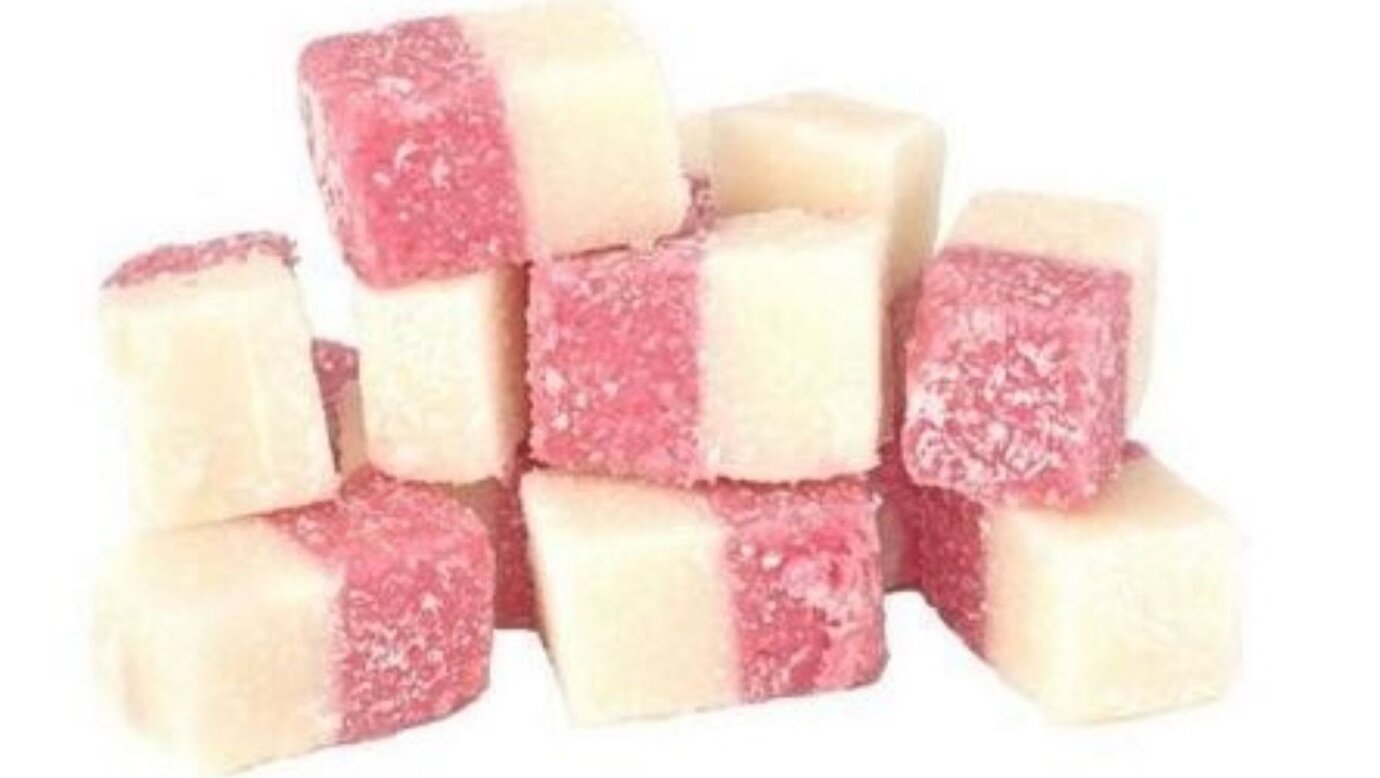 Pink and white cubes of creamy coconut ice dusted with coconut