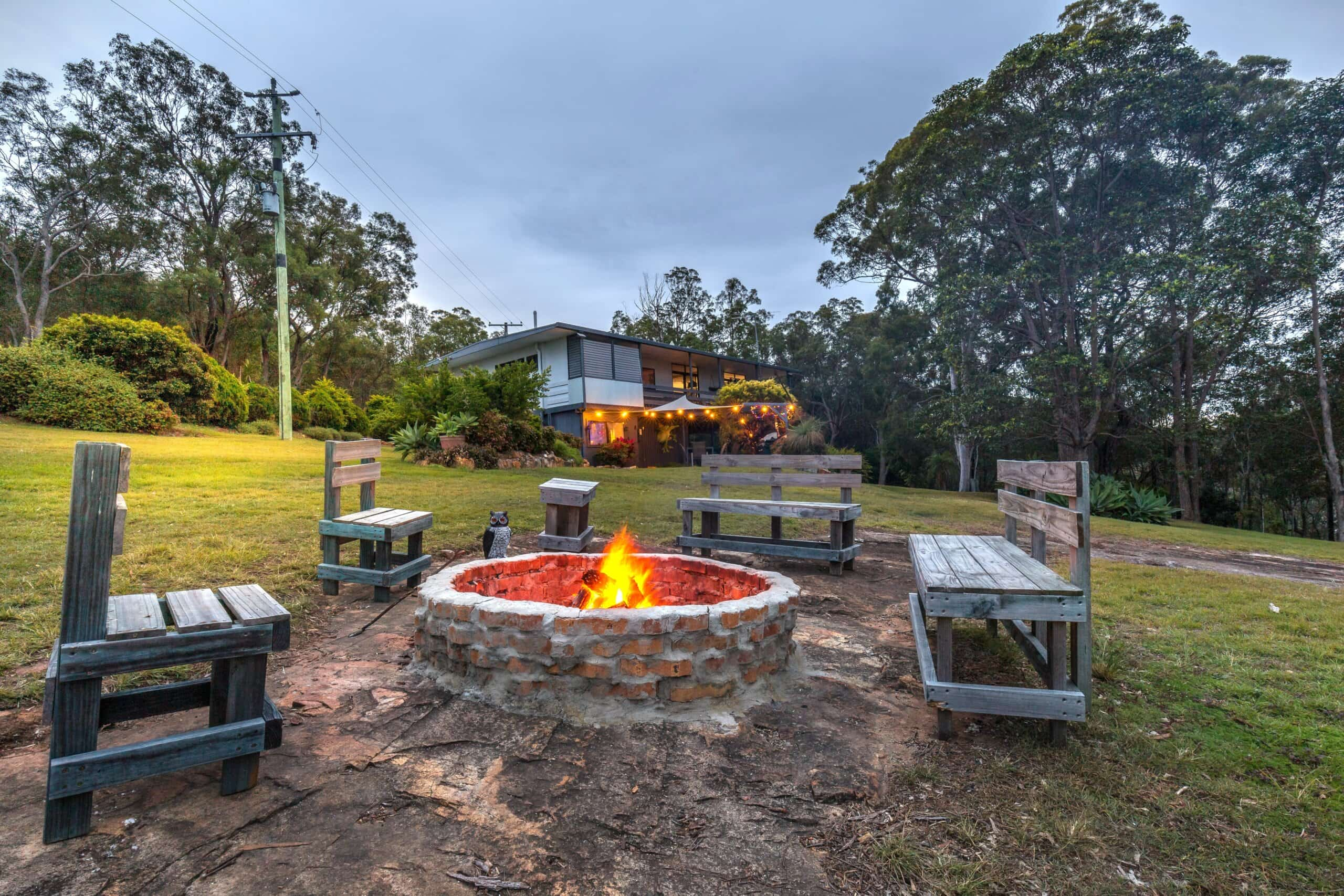 the view from the firepit which is lit and flames are  crackling with Moogie House in the background