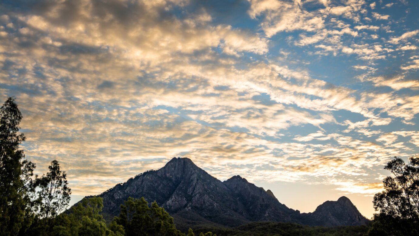 Mountain range silhouetted against a cloudy sky at sunset