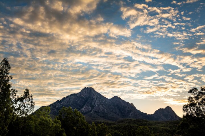 Mountain range silhouetted against a cloudy sky at sunset