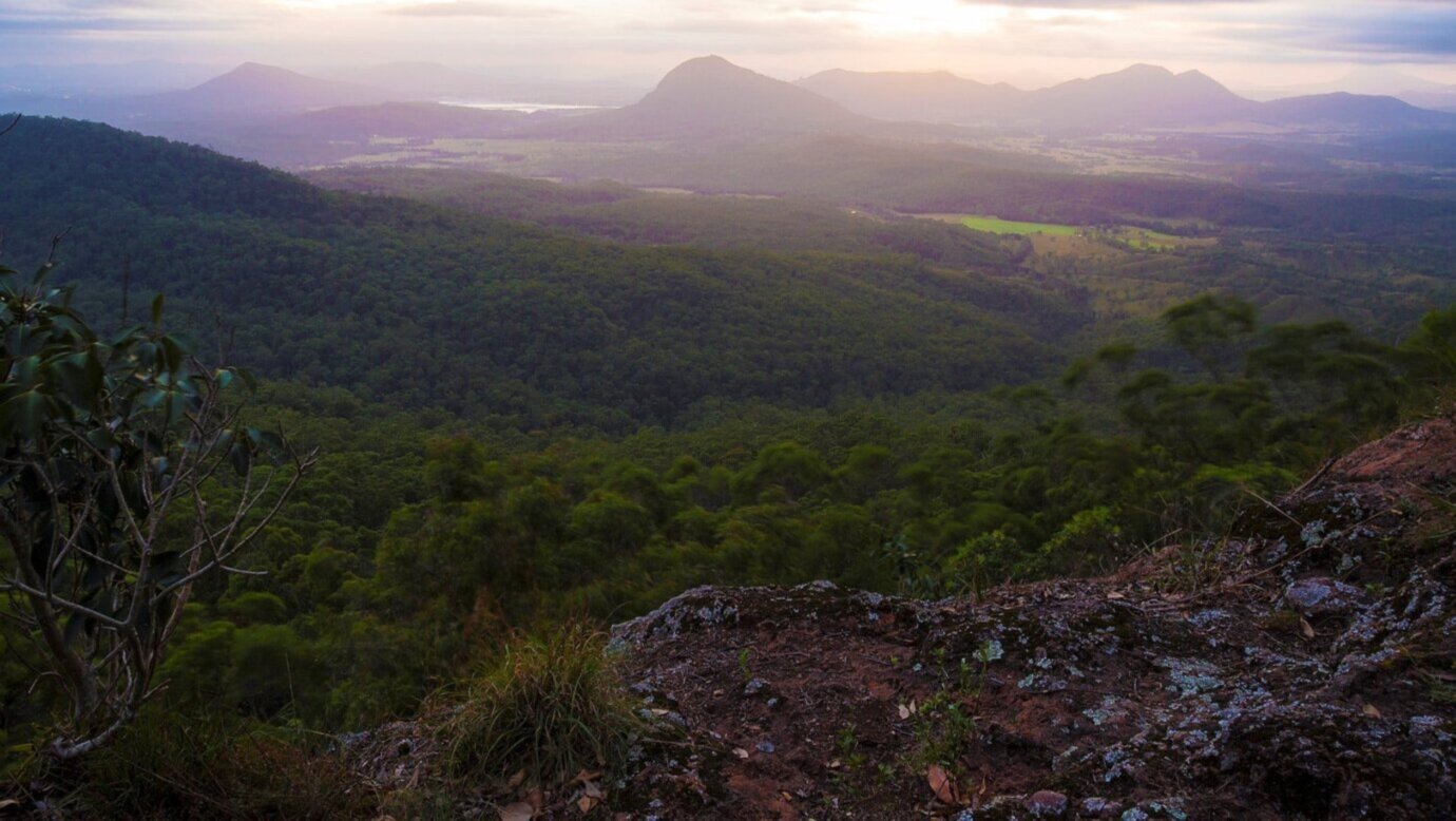 A view over a green valley with a mountain range behind