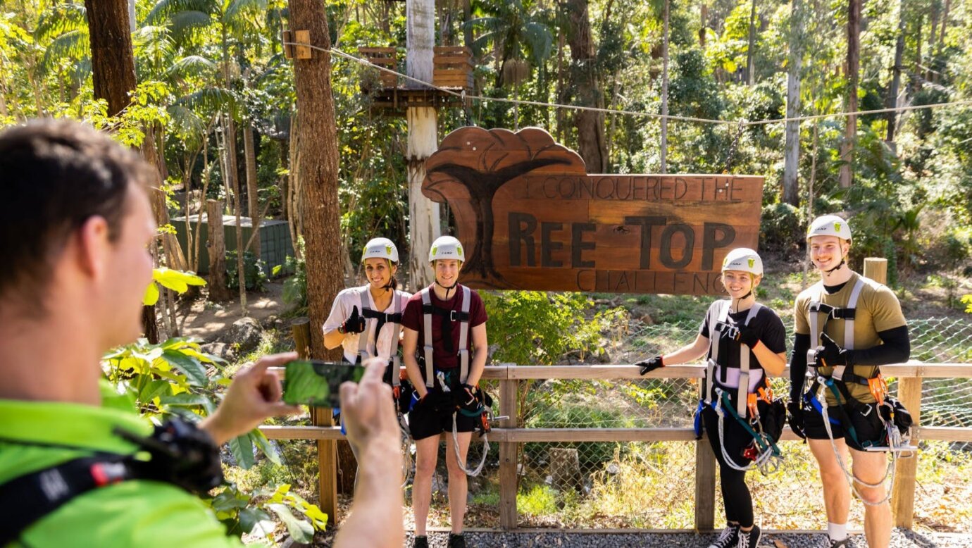 Group of climbers getting a photo infront of our TreeTop Challenge sign