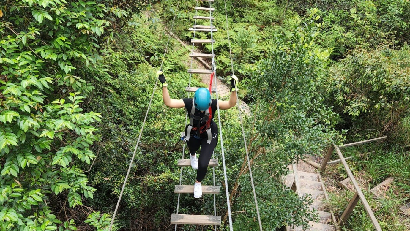 Woman walking along suspended bridge