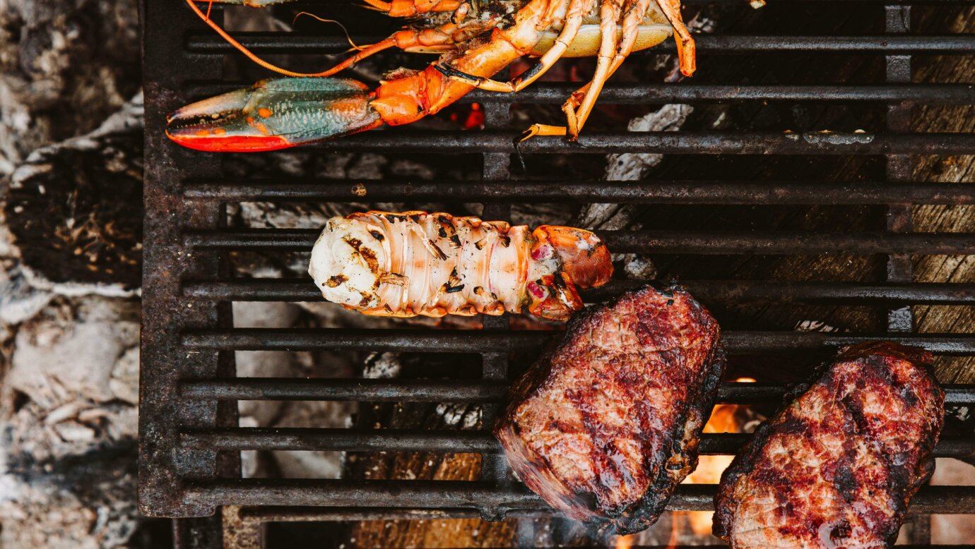Redclaw crayfish and steak cooking over coals