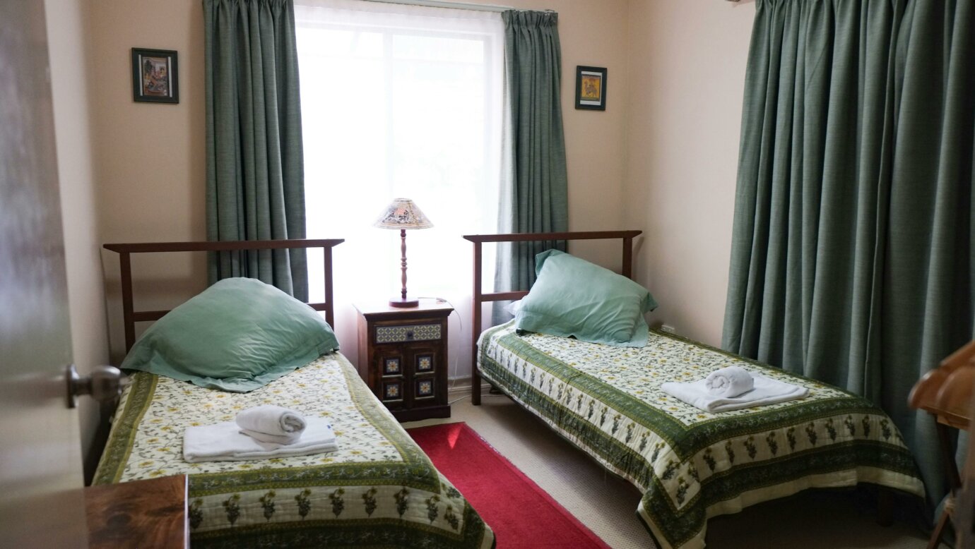 twin share bedroom with green curtains at Nirvana