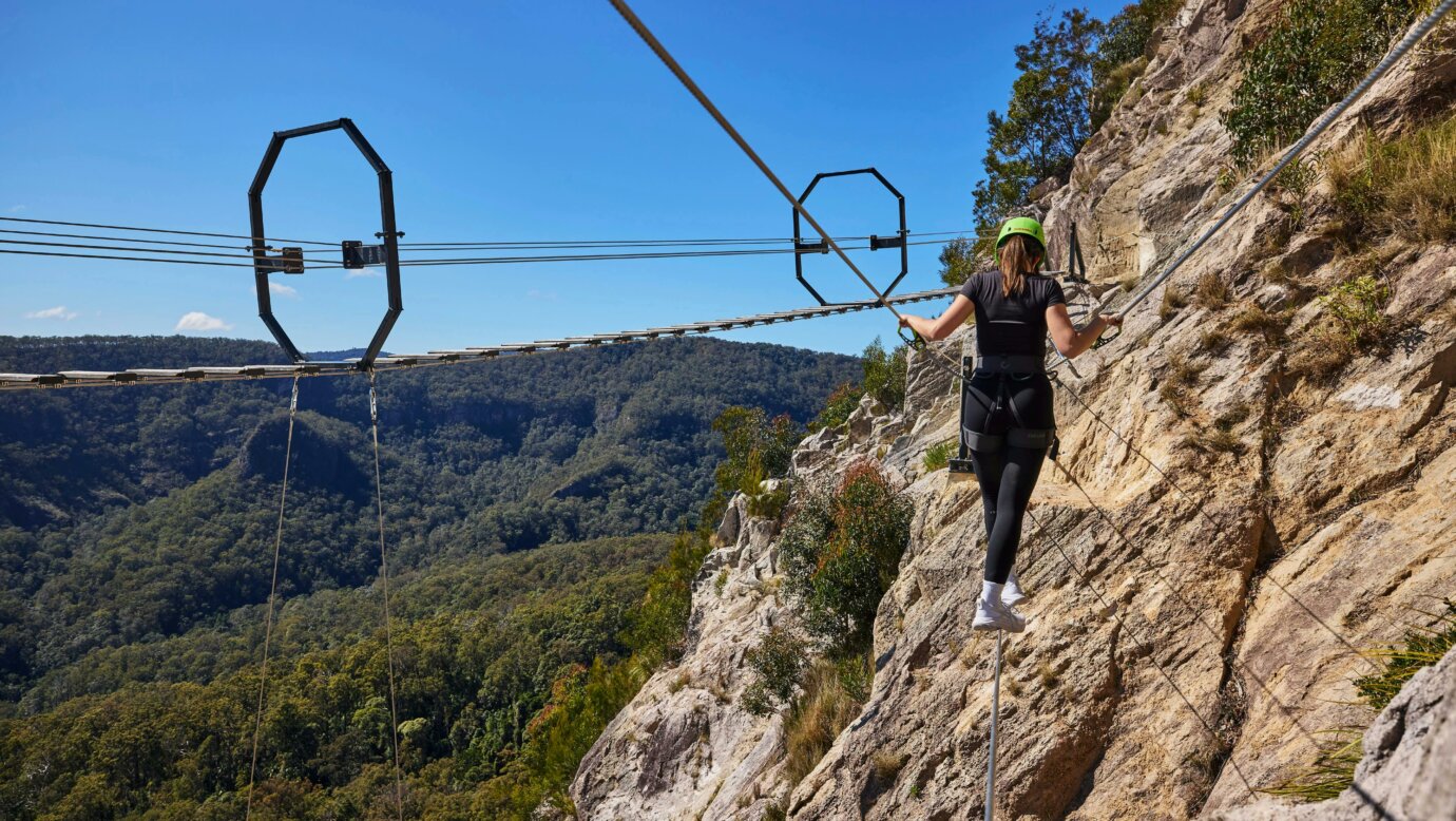 Woman walking across Via Ferrata at Happitat Adventure Park