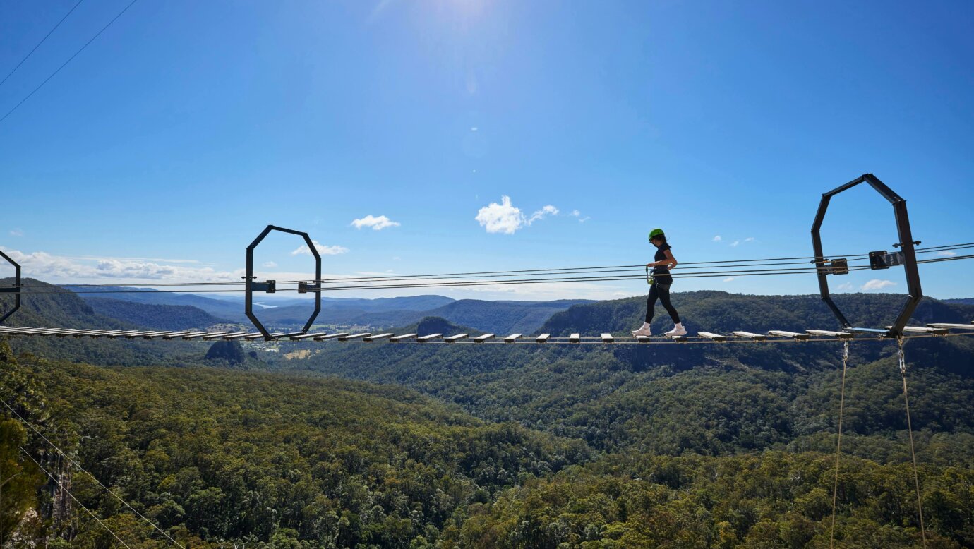 Woman walking across Via Ferrata at Happitat Adventure Park