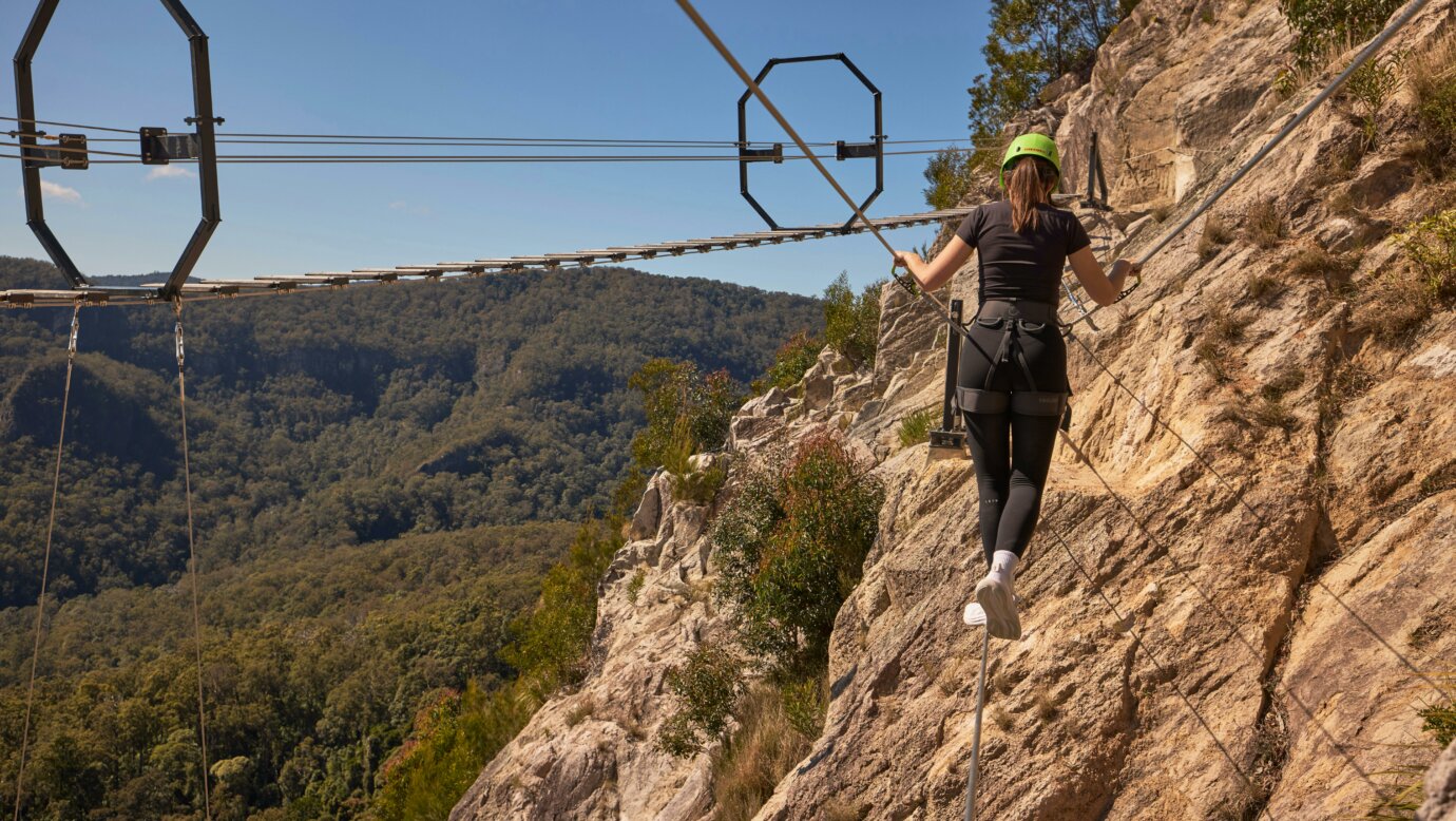 Woman walking across Via Ferrata at Happitat Adventure Park