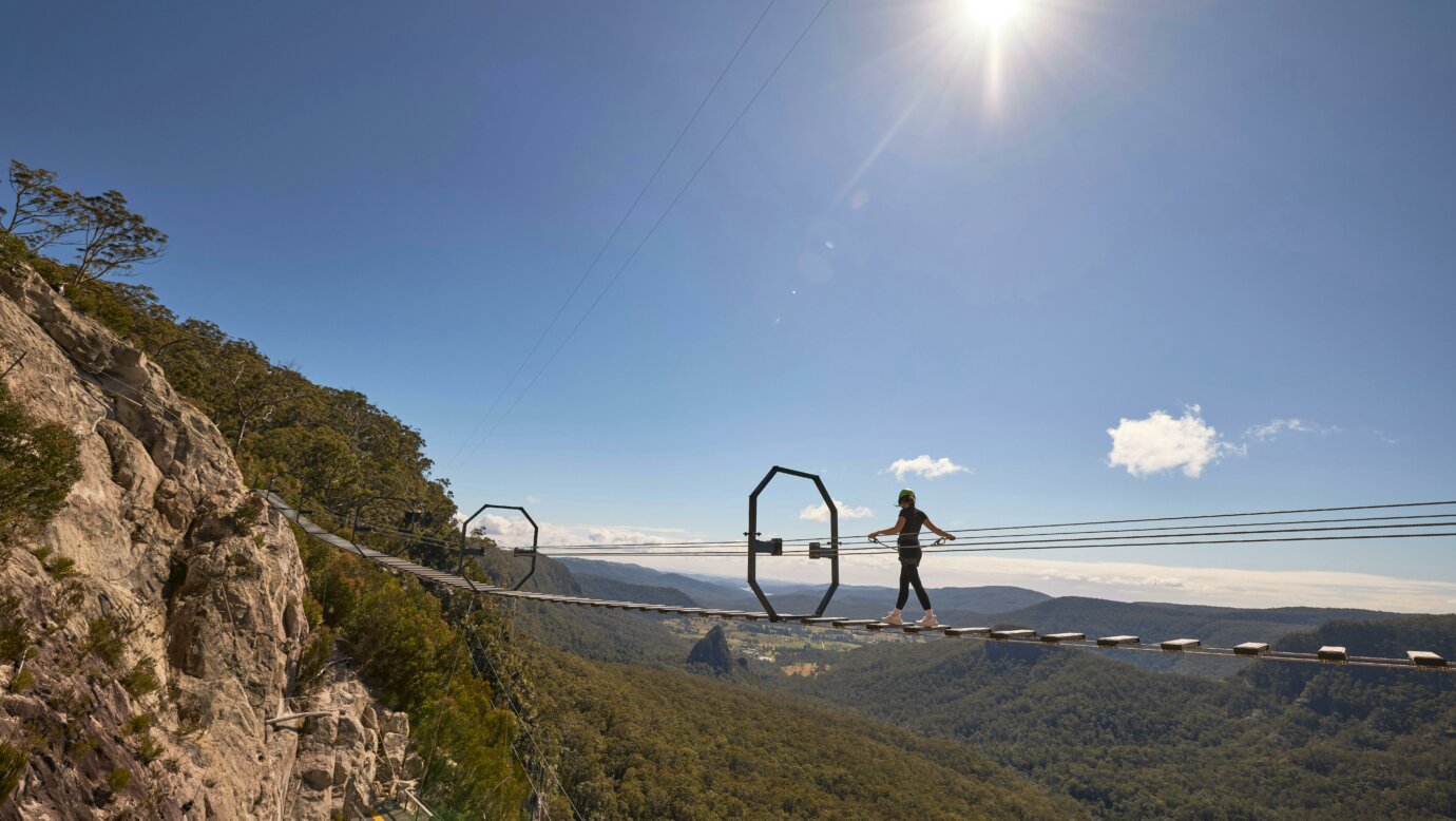 Woman walking across Via Ferrata at Happitat Adventure Park