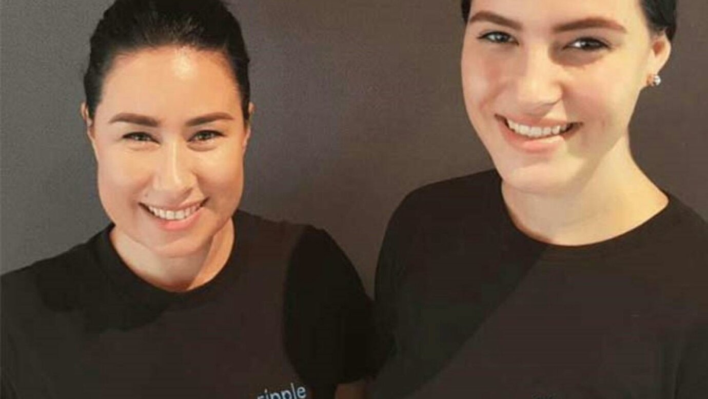 Two Ripple massage therapists smiling in black shirts with blue Ripple logo