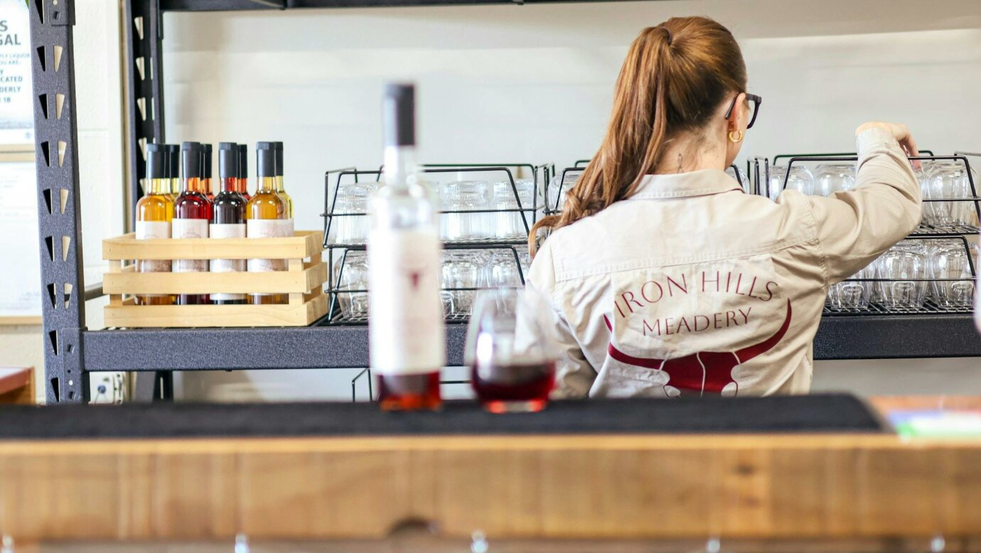 Katrina standing behind bar with mead in glass